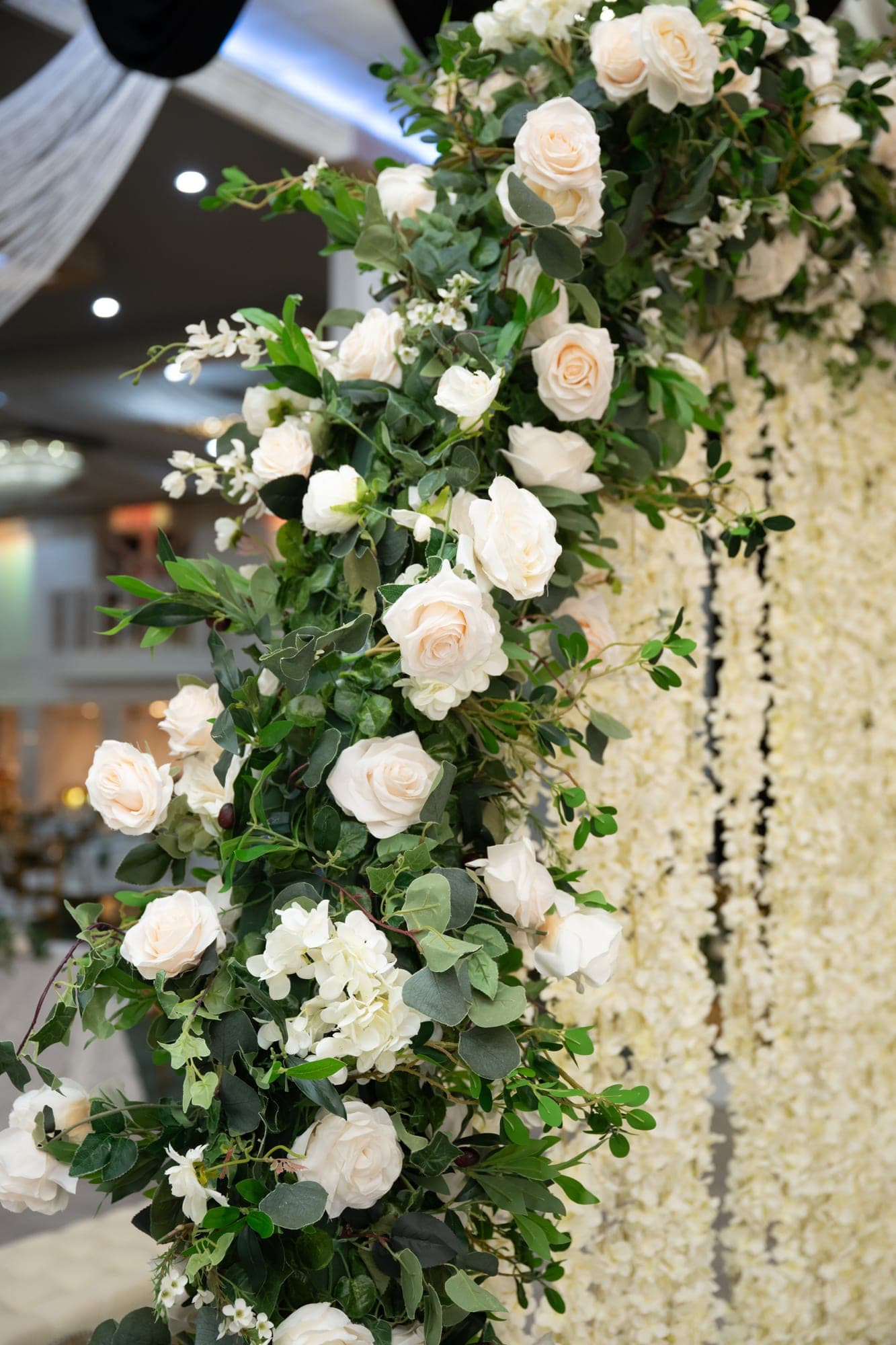 A close view of ivory roses and greenery framing the wedding stage